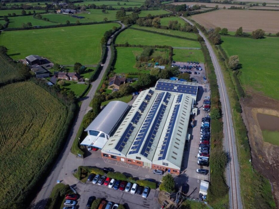 A picture of the modern Brotherwood production facility, surrounded by landscaped greenery and showcasing its solar-powered design.