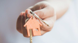 A close-up of a hand holding keys with a house-shaped keychain