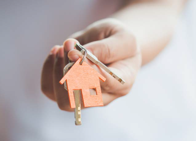 A close-up of a hand holding keys with a house-shaped keychain