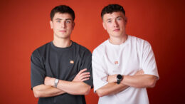 Jordan (right) and his brother Cian (left), in front of a red background at a photoshoot for Alzheimer's Research UK.