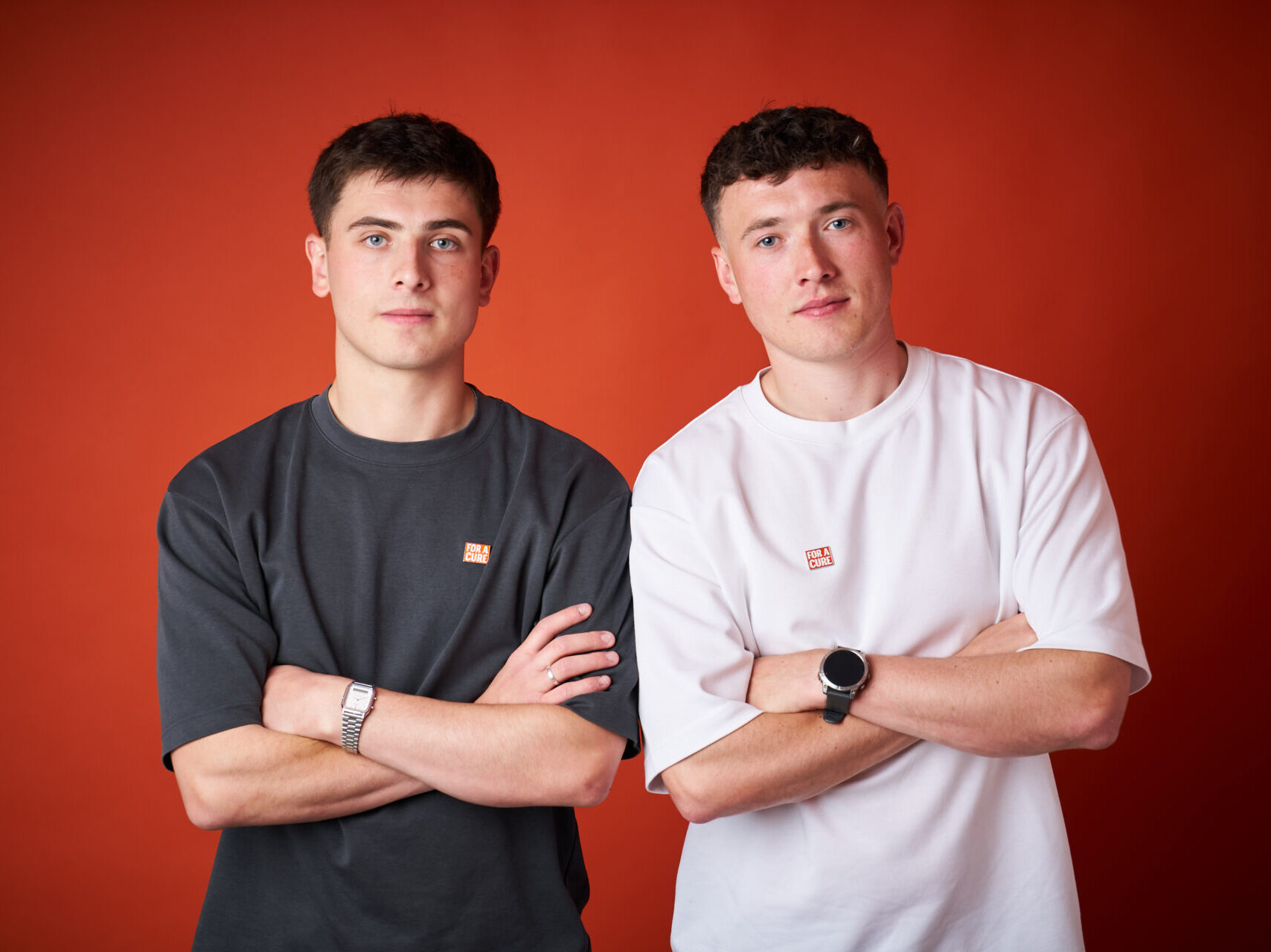 Jordan (right) and his brother Cian (left), in front of a red background at a photoshoot for Alzheimer's Research UK.