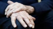 An image of an elderly person's hands resting on each their knee.