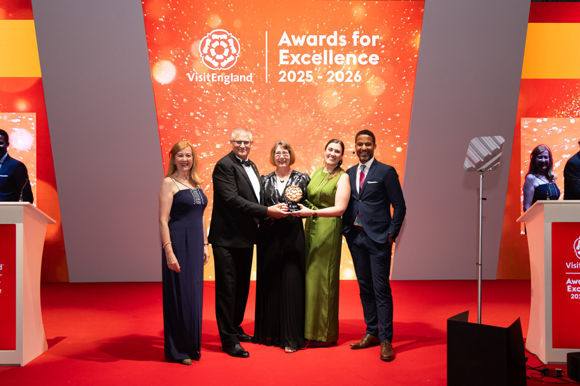 Winners from Hoe Grange Holidays, Gold winner of the Accessible & Inclusive
Tourism Award, at the VisitEngland Awards for Excellence 2026, pictured on stage with host Sean
Fletcher and Lady Victoria Borwick, VisitEngland Chair, at Aerospace Bristol.