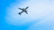 An airplane seen from below with a bright blue sky behind.